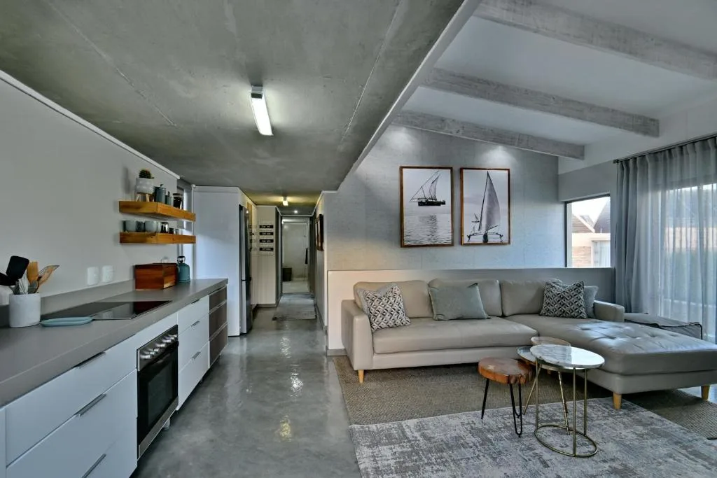 Modern open-plan lounge with beige sectional sofa and nautical wall art