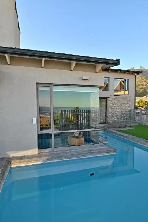 Modern swimming pool with deck overlooking ocean and garden landscape