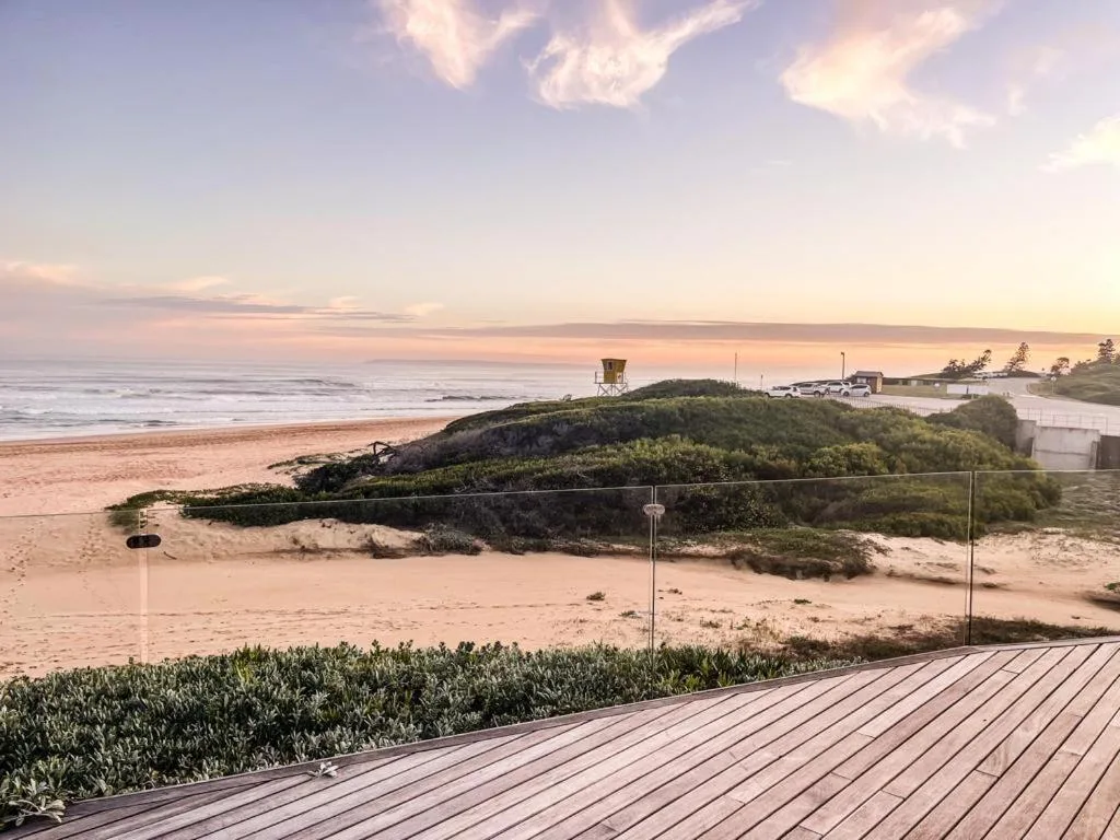 Sunset coastal view from deck overlooking beach, dunes, and ocean horizon