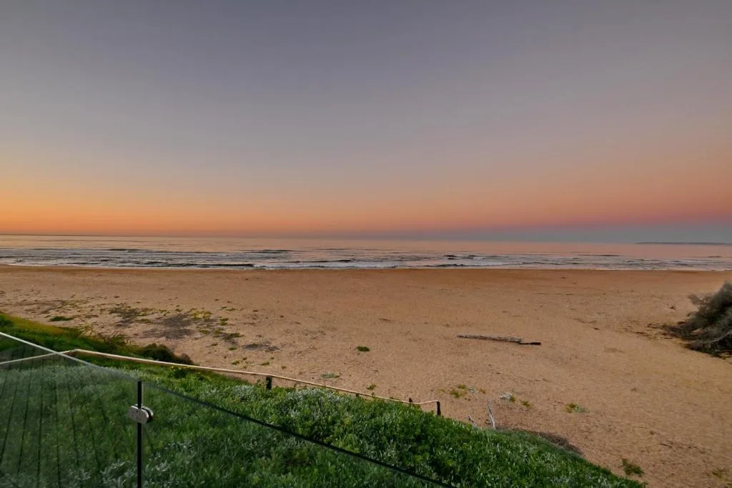 Sunset over sandy beach and ocean waves from property deck