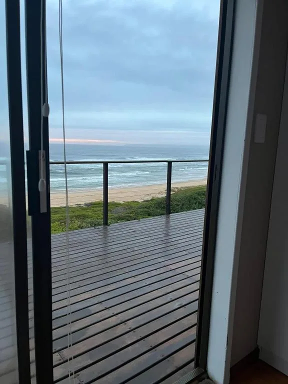 Wooden deck overlooking pristine beach and ocean at sunset