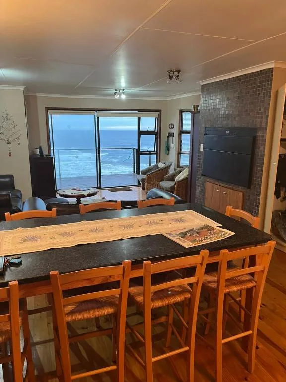 Dining area with wooden table and orange chairs overlooking ocean view