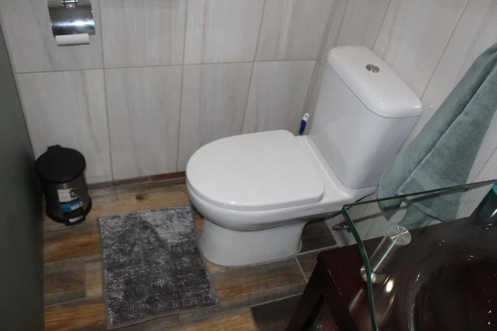 Modern white toilet and cistern in tiled bathroom with wooden flooring