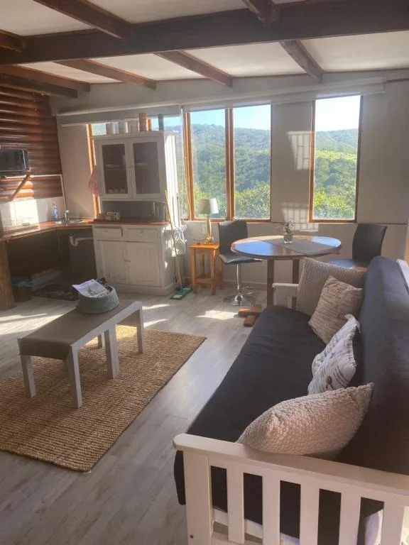 Open-plan lounge with sofa, dining table, and mountain views through large windows