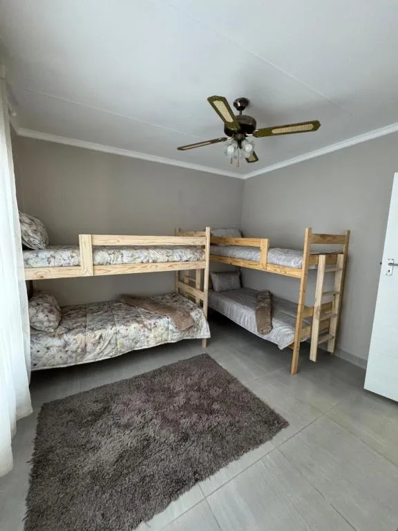 Bright bedroom with two wooden bunk beds and ceiling fan