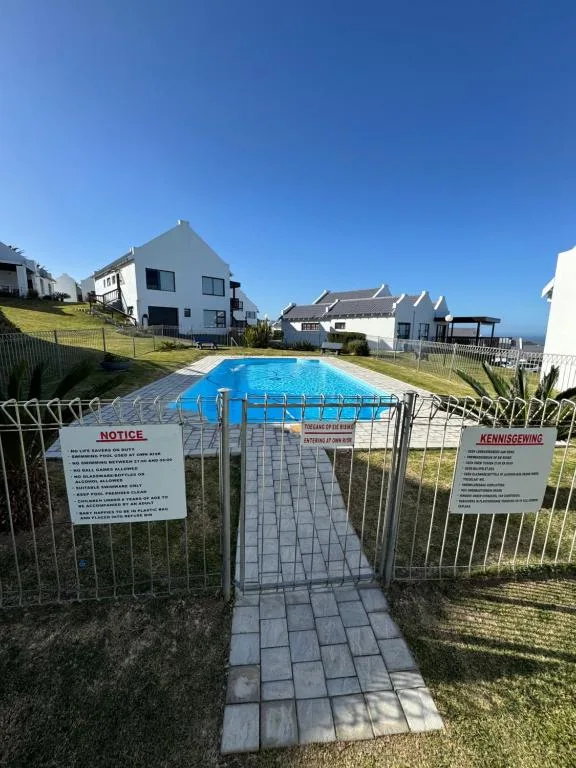 Gated swimming pool with blue cover and residential buildings beyond