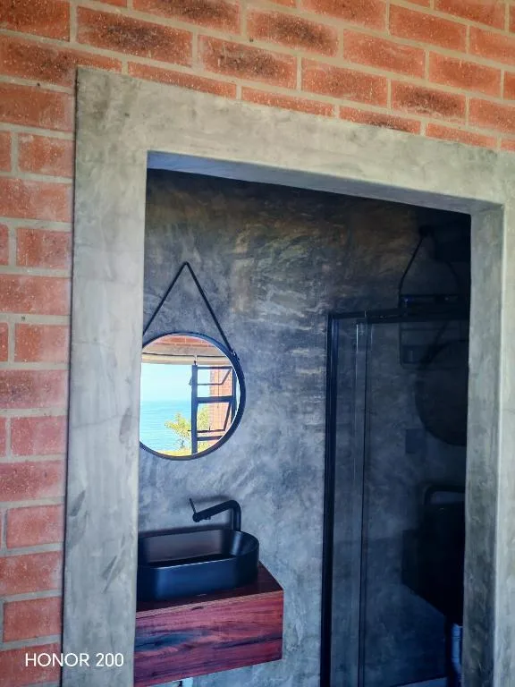 Modern decorative round mirror and dark basin on coastal-view bathroom wall