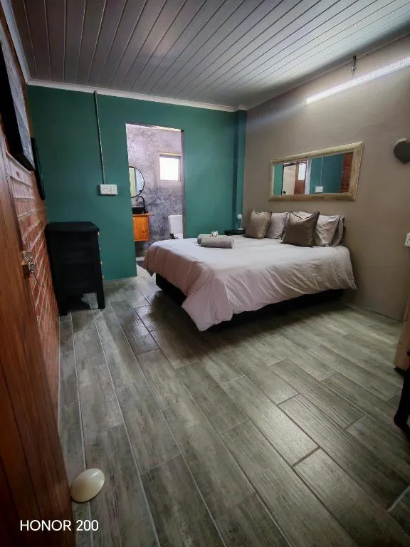 Bright bedroom with queen bed, green accent wall, and mirror