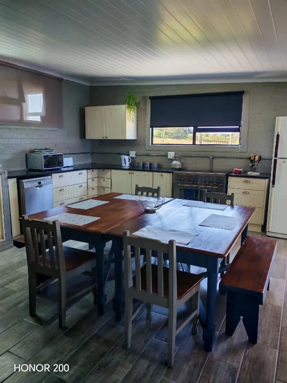 Open-plan kitchen with cream cabinetry, dining table, and window view