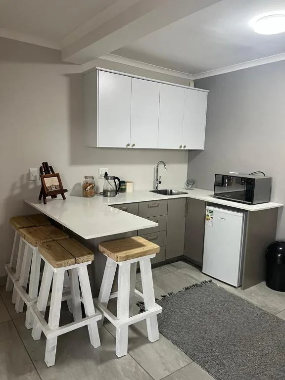 Modern kitchen with white cabinetry, white appliances, and breakfast bar seating