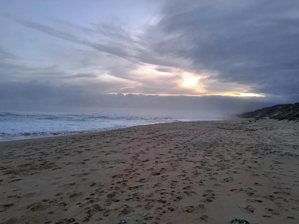 Scenic beach sunset with dramatic clouds over ocean and coastline