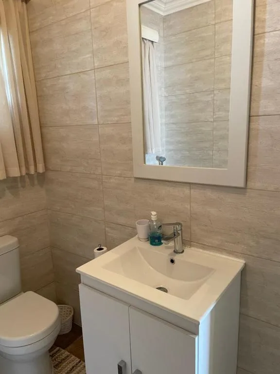 Modern bathroom with white vanity, mirror, and beige tile walls