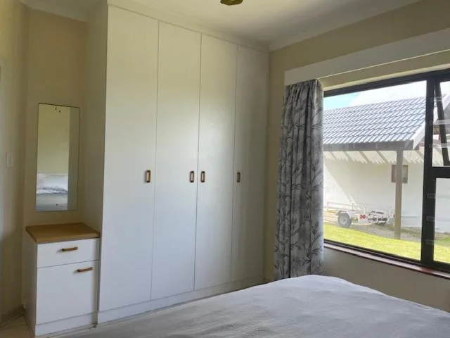 Spacious bedroom with built-in white wardrobes and garden views