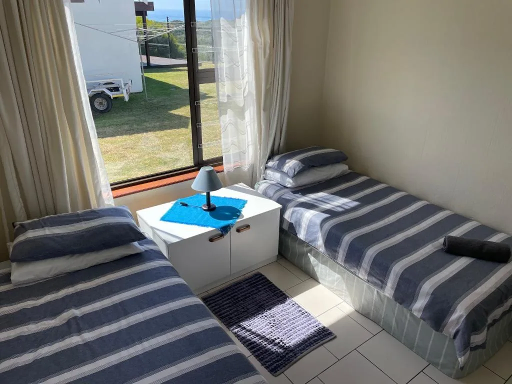 Twin bedroom with striped bedding and garden view doors opening outside