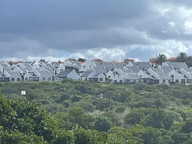Distant view of white-roofed coastal cottages nestled among lush green vegetation