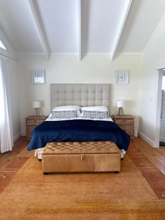 Bright bedroom with queen bed, upholstered headboard, wooden nightstands, leather bench