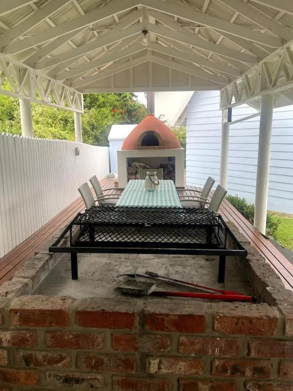 Covered outdoor dining area with brick fireplace and garden views