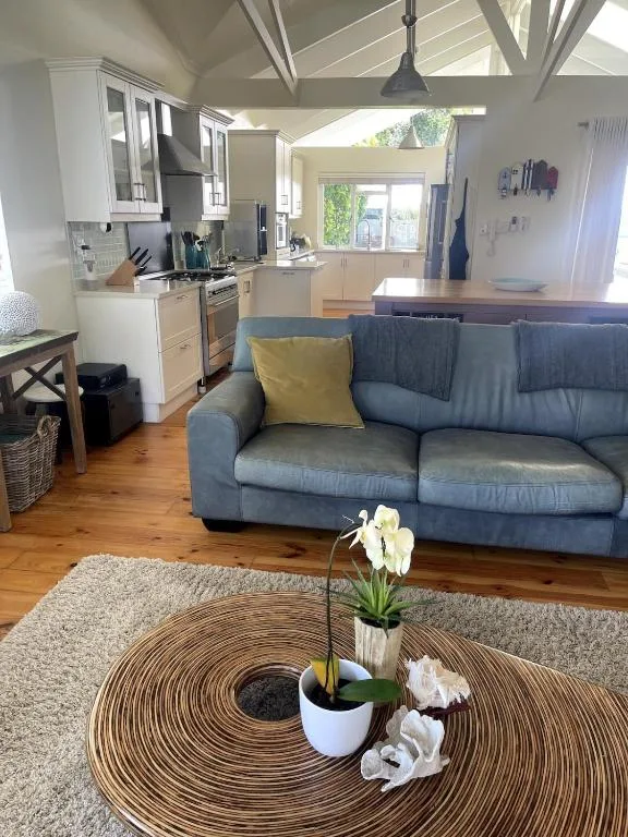 Open-plan lounge with blue sofa, natural light, and modern kitchen visible