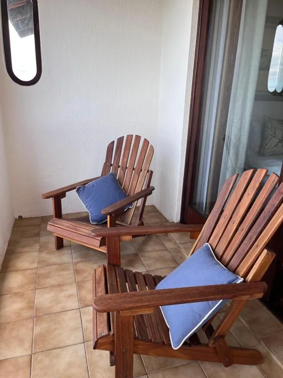 Wooden Adirondack chairs with blue cushions on a tiled patio
