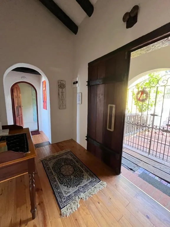 Interior entryway with arched doorway and dark wooden doors opening to garden