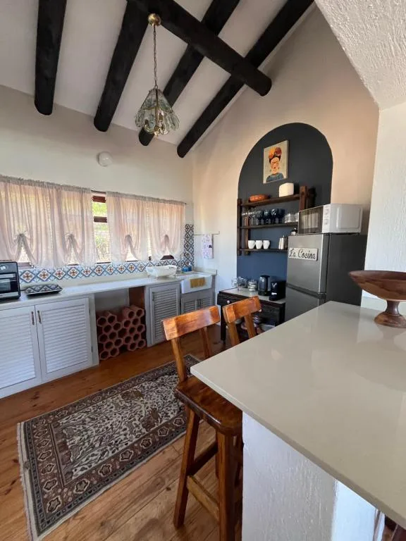 Open-plan kitchen with white cabinetry, dining table, and exposed beams