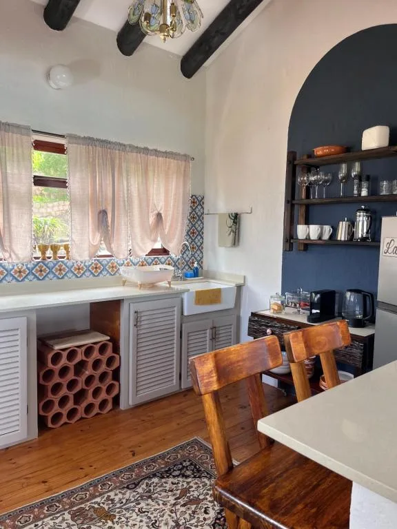 Modern kitchen with white cabinetry, blue feature wall shelving, and wooden dining chairs