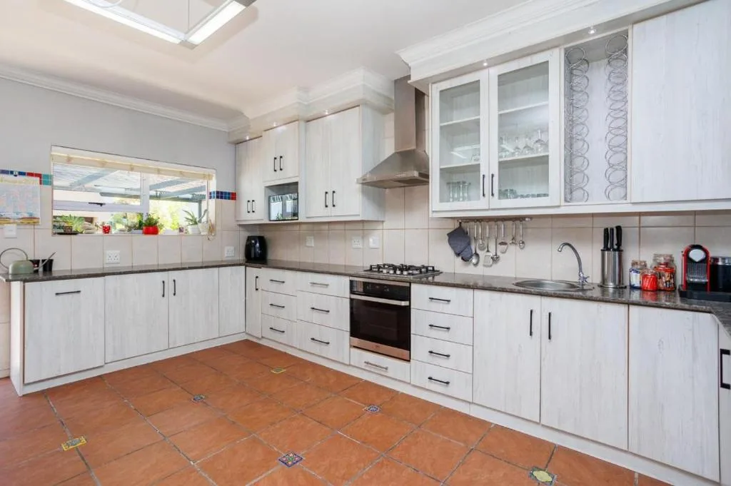 Modern white kitchen with gas stove, built-in oven, and terracotta tile floors