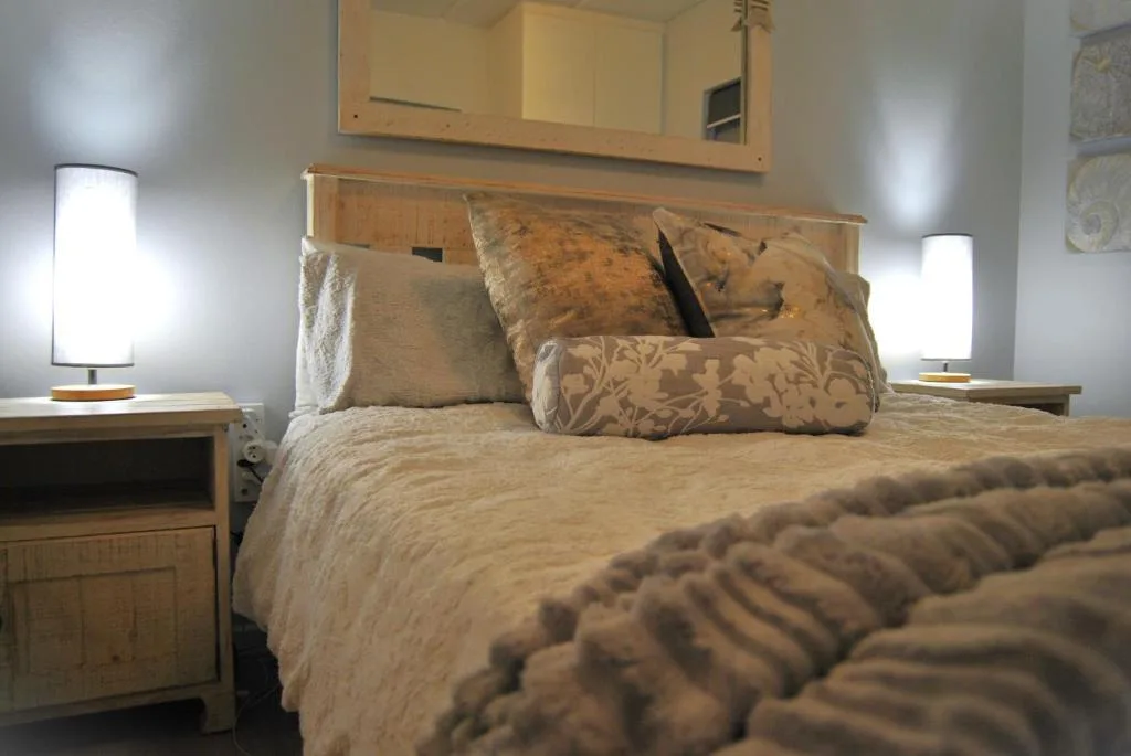 Comfortable bed with decorative pillows and bedside lamps in warm tones