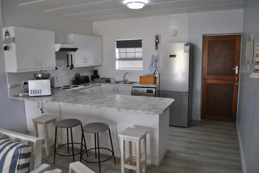 Modern kitchen with white cabinetry, marble countertop island, and stainless steel appliances