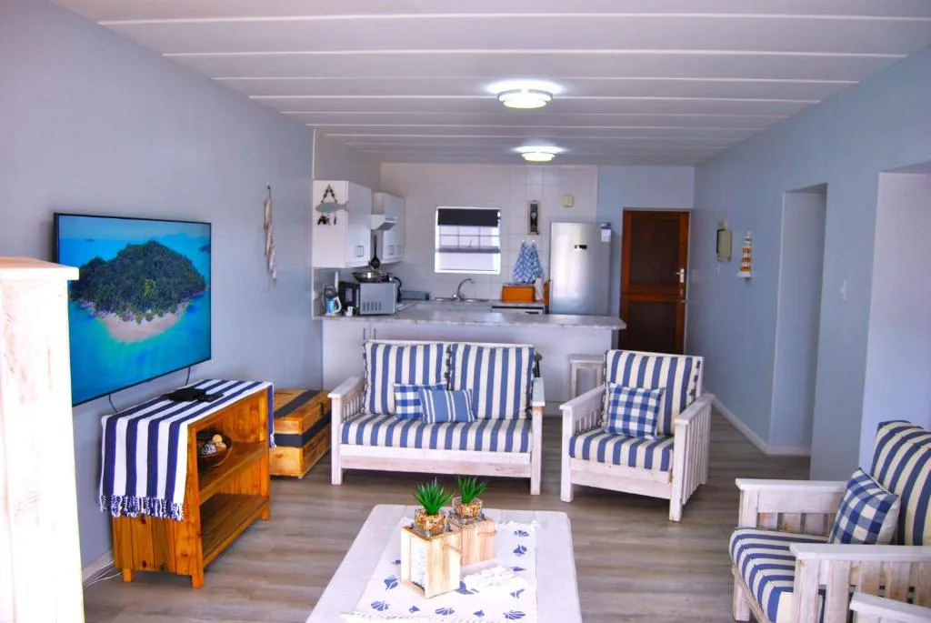 Open-plan lounge with striped blue and white furniture and kitchen area