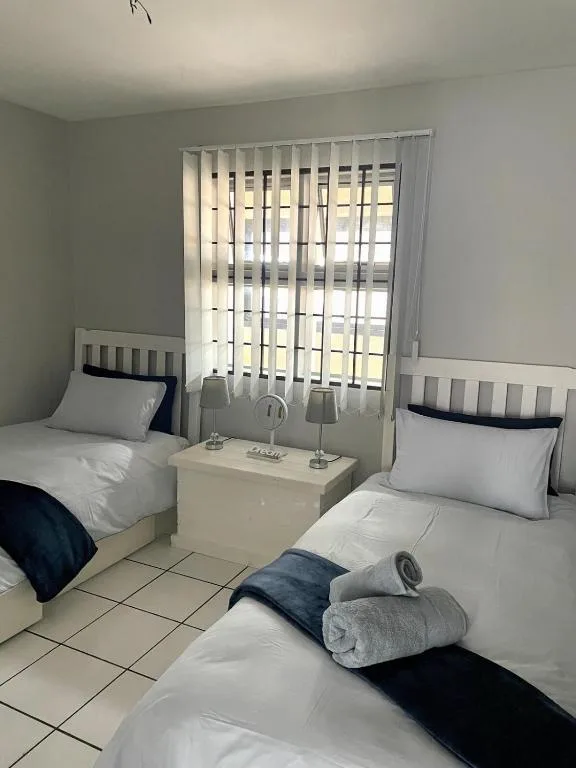 Bright twin bedroom with white beds and navy accents, natural light