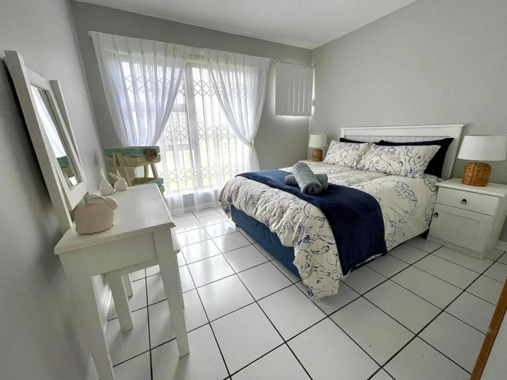 Bright bedroom with double bed, white furniture, and garden view doors