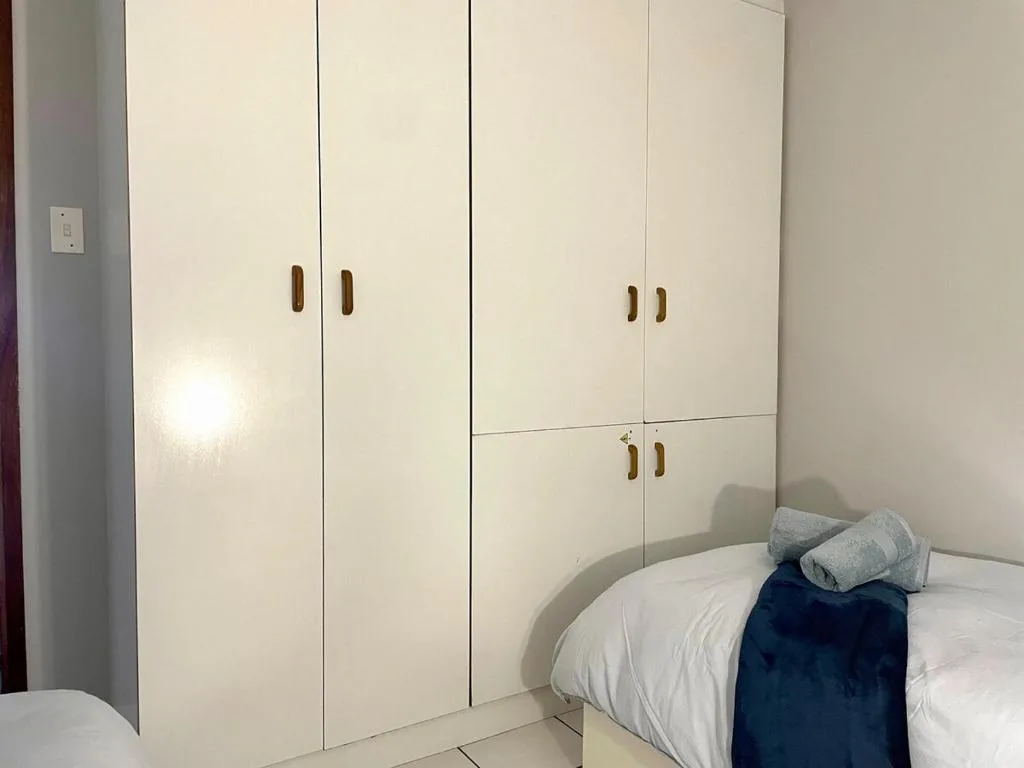 Bedroom with white fitted wardrobes and neatly made bed with pillows