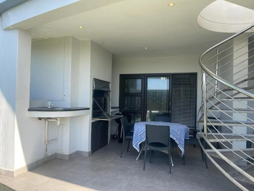 Covered outdoor patio with dining table and modern spiral staircase