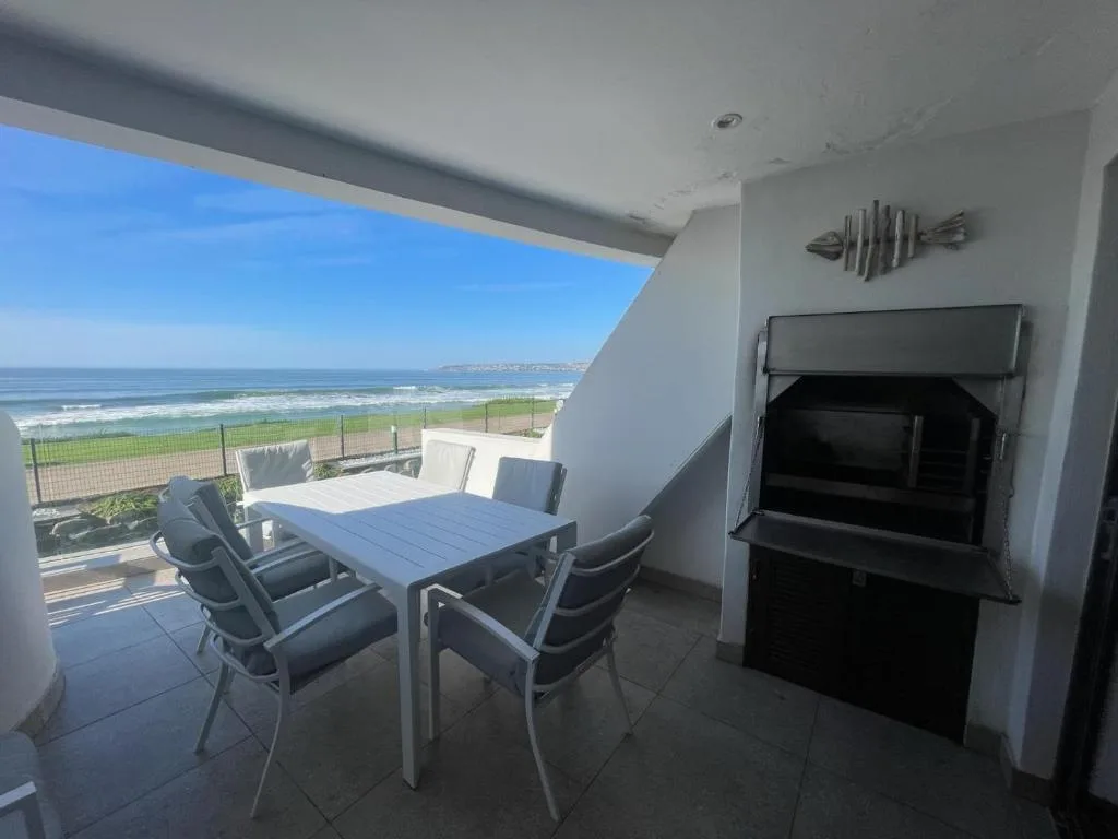 Beachfront balcony with dining table overlooking ocean and coastline