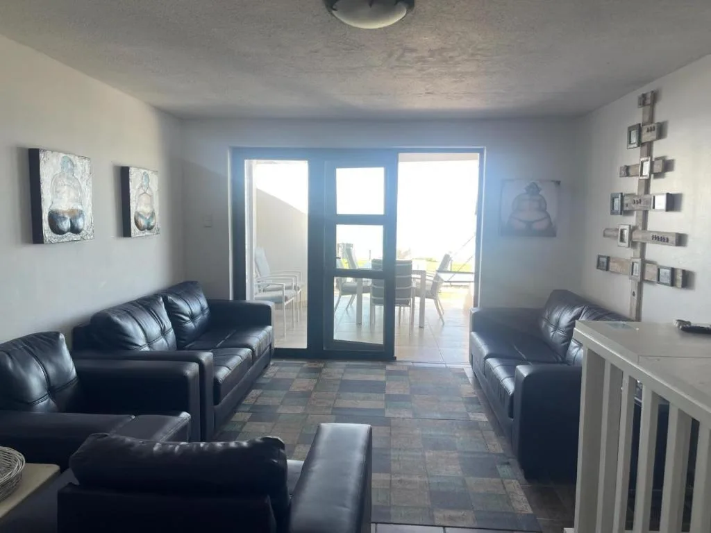 Spacious lounge with black leather sofas and sliding doors to deck