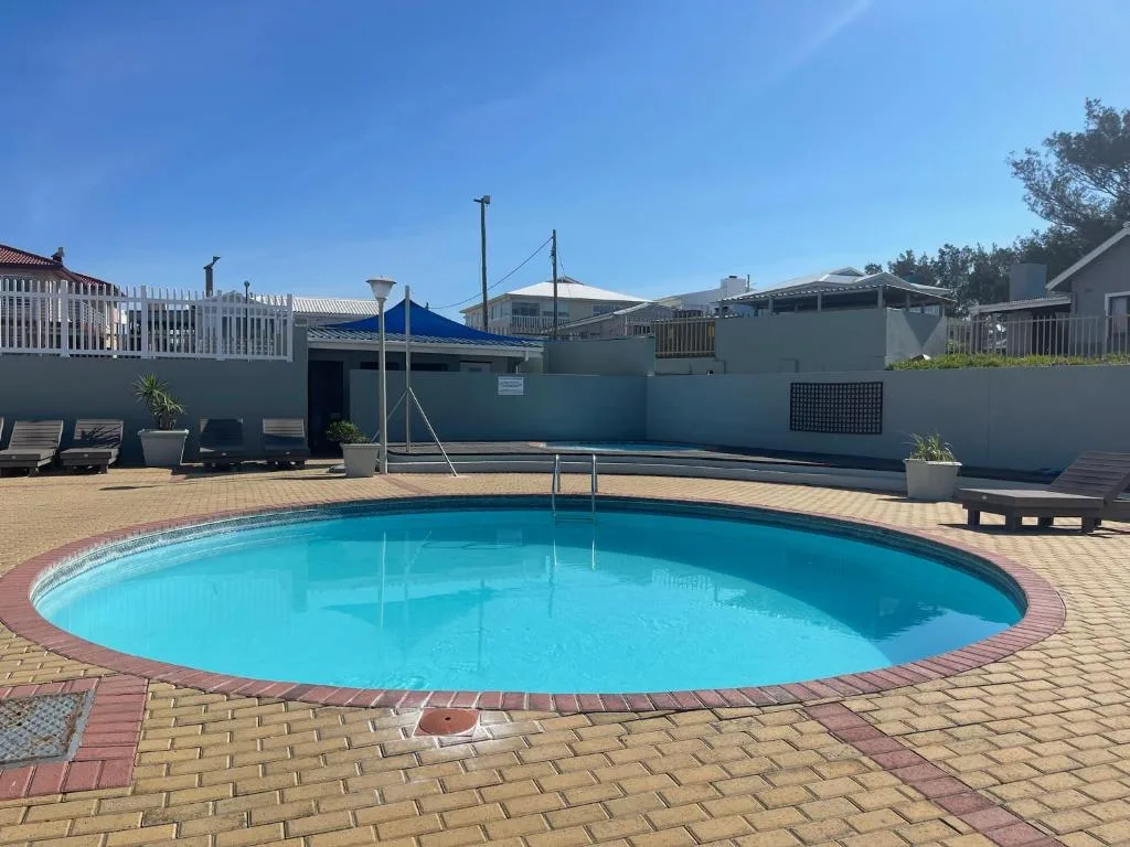 Bright blue circular swimming pool with brick surround and loungers