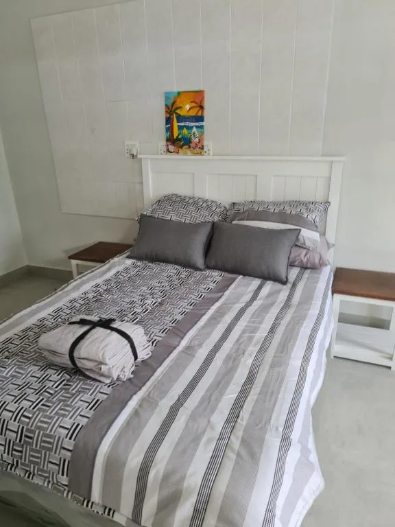 Bright bedroom with white headboard, patterned gray bedding, decorative artwork