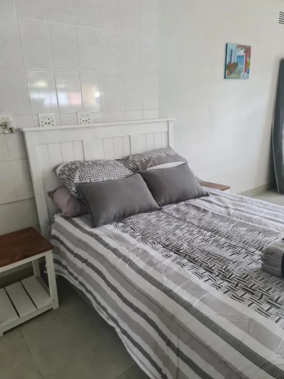 Clean bedroom with white wooden bed frame and patterned bedding