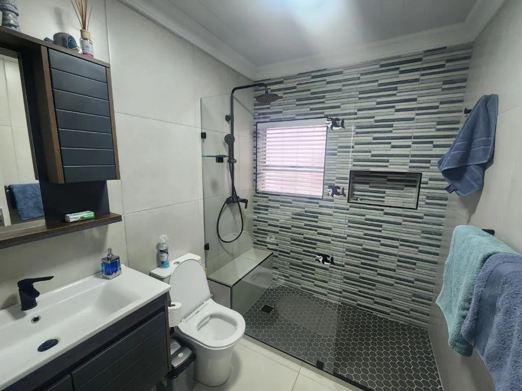 Modern bathroom with striped tile wall, walk-in shower, vanity and toilet