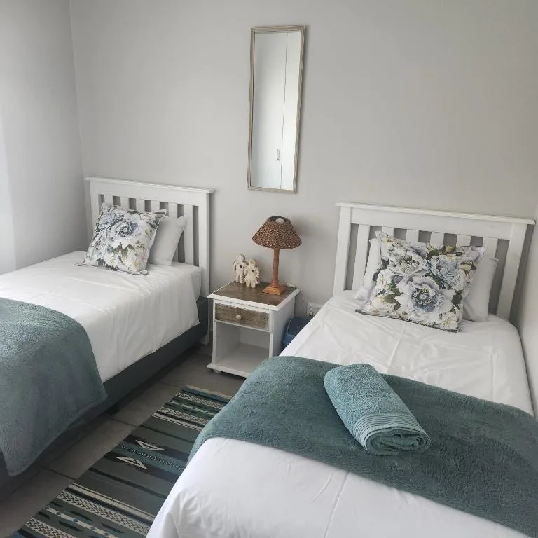 Twin bedroom with white frames, patterned pillows, and teal blankets