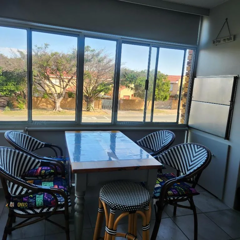 Outdoor seating area with table and striped chairs overlooking garden trees
