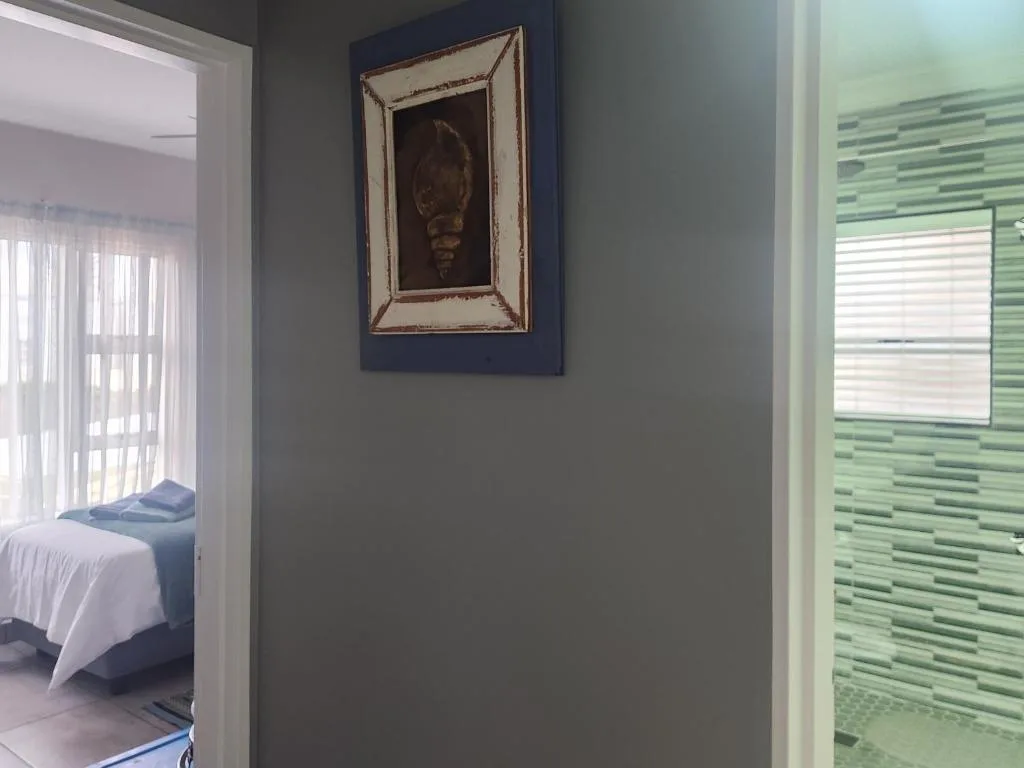 Modern interior hallway with framed artwork and green tiled bathroom visible