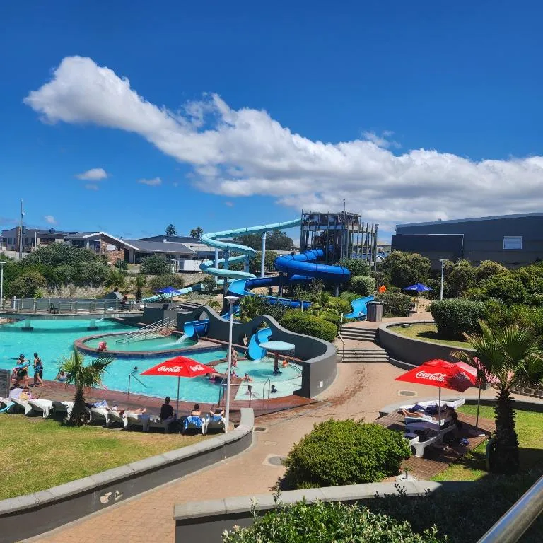 Bright aquamarine water park with blue slides and red umbrellas visible