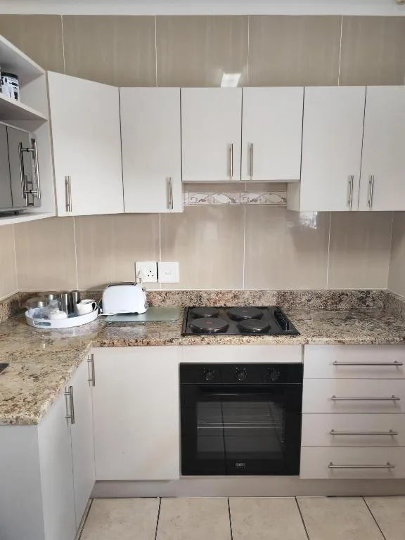 Modern white kitchen with granite counters and black built-in oven