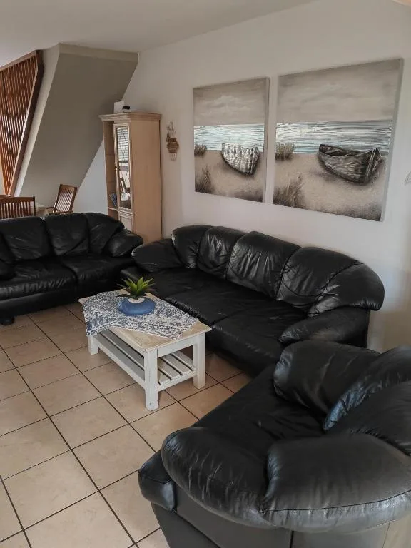 Black leather sofa and armchair with coastal artwork and white coffee table