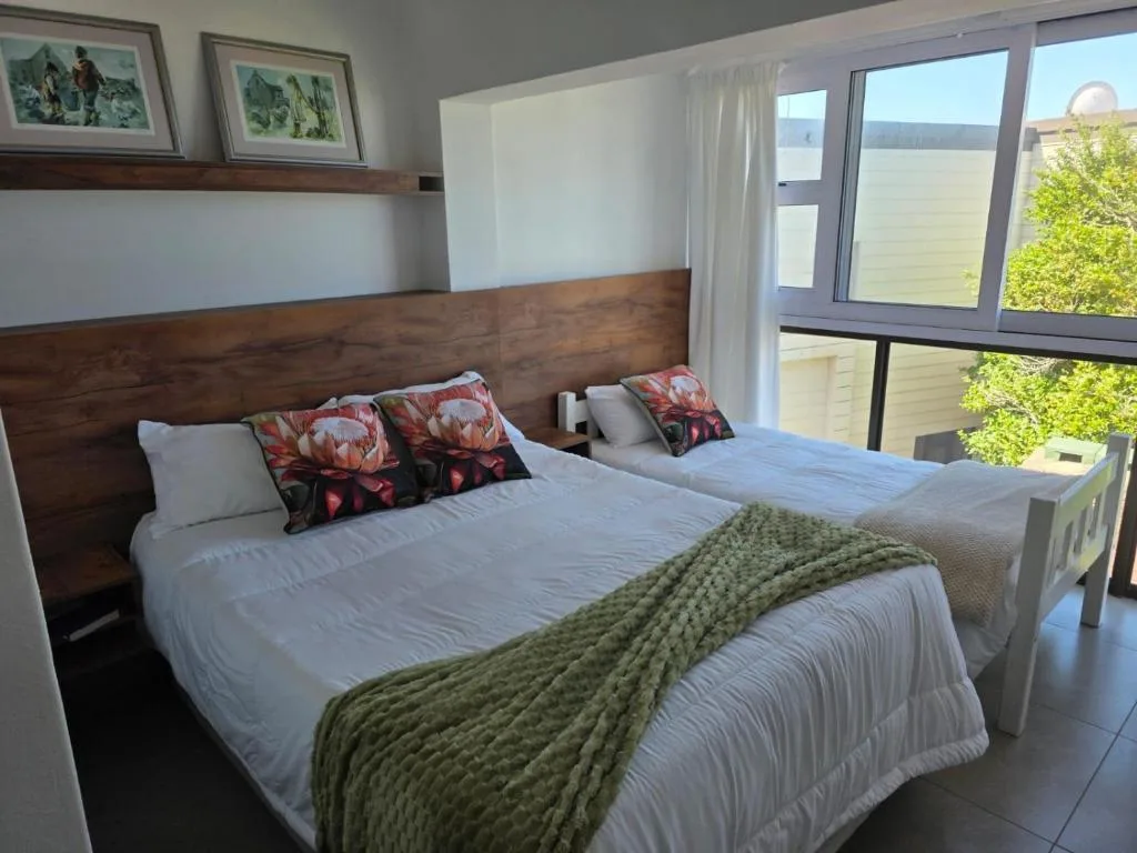 Bright bedroom with double bed, wooden headboard, and garden views through sliding doors