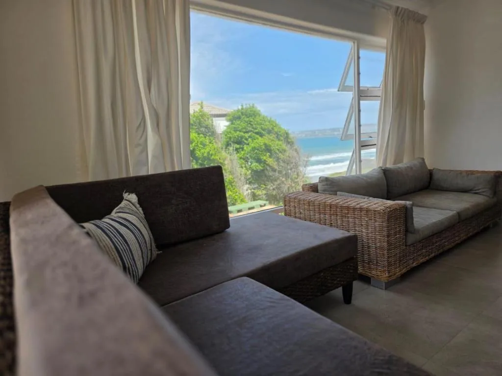 Modern lounge with dark sofas overlooking ocean and beach views through large windows