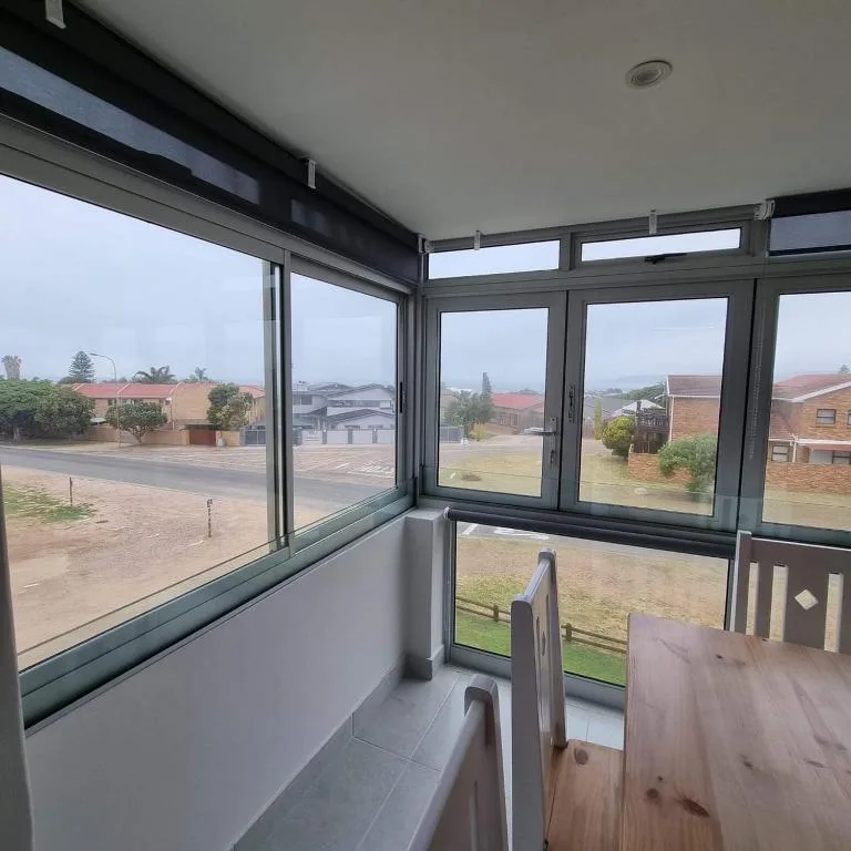 Enclosed patio with large windows overlooking residential garden route neighborhood