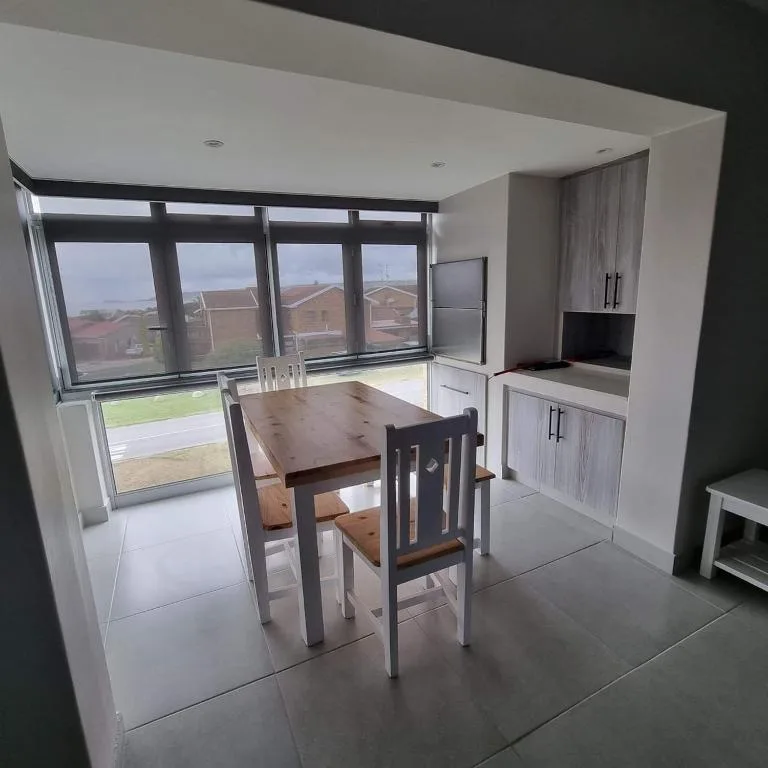 Modern dining table with chairs beside kitchen and large windows overlooking garden